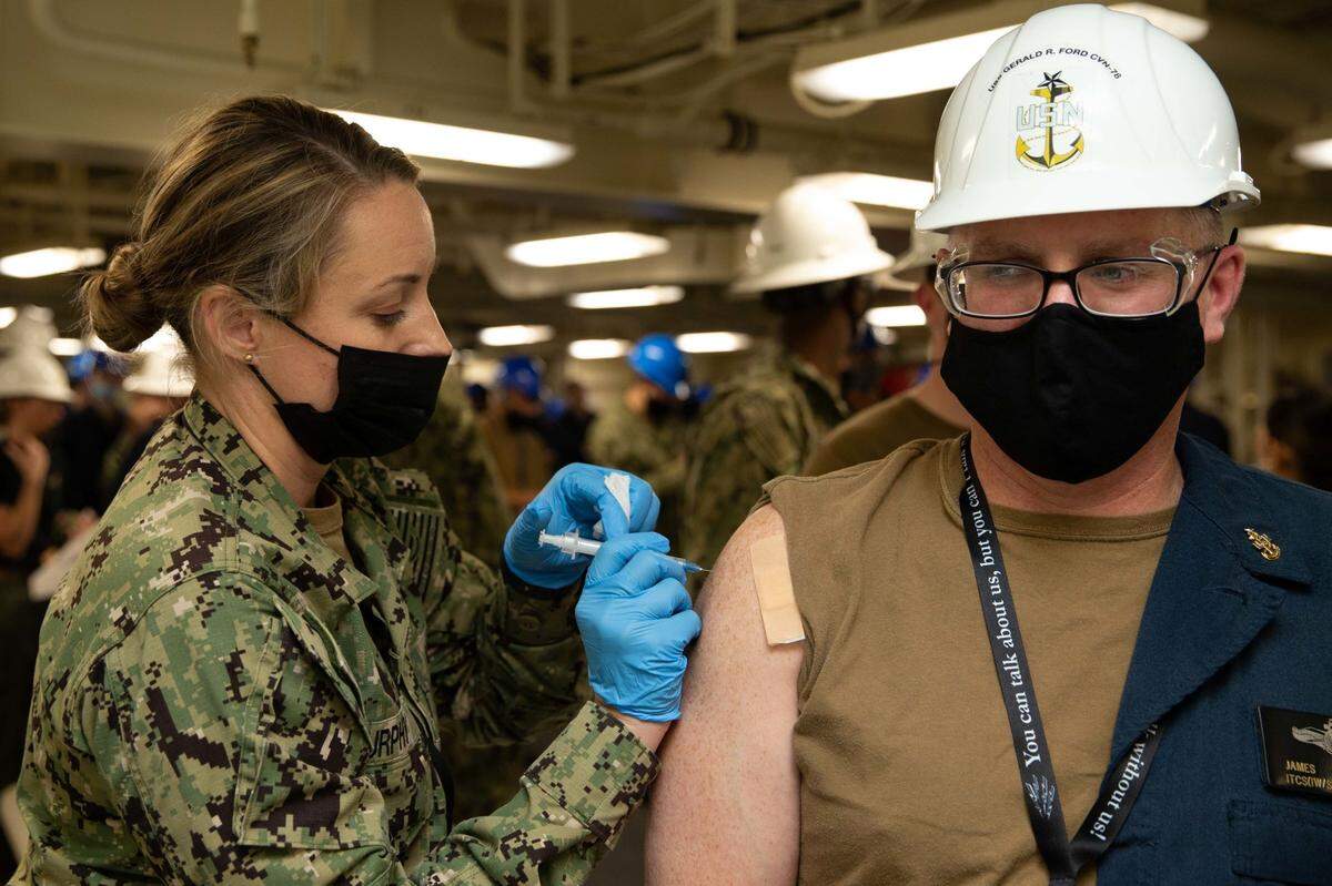 Lt. Cmdr. Susan Murphy gives a flu shot to Senior Chief Information Systems Technician James Meggison aboard the USS Gerald R. Ford on Oct. 21, 2021, in Newport News, Virginia. Murphy is from Modesto CA.