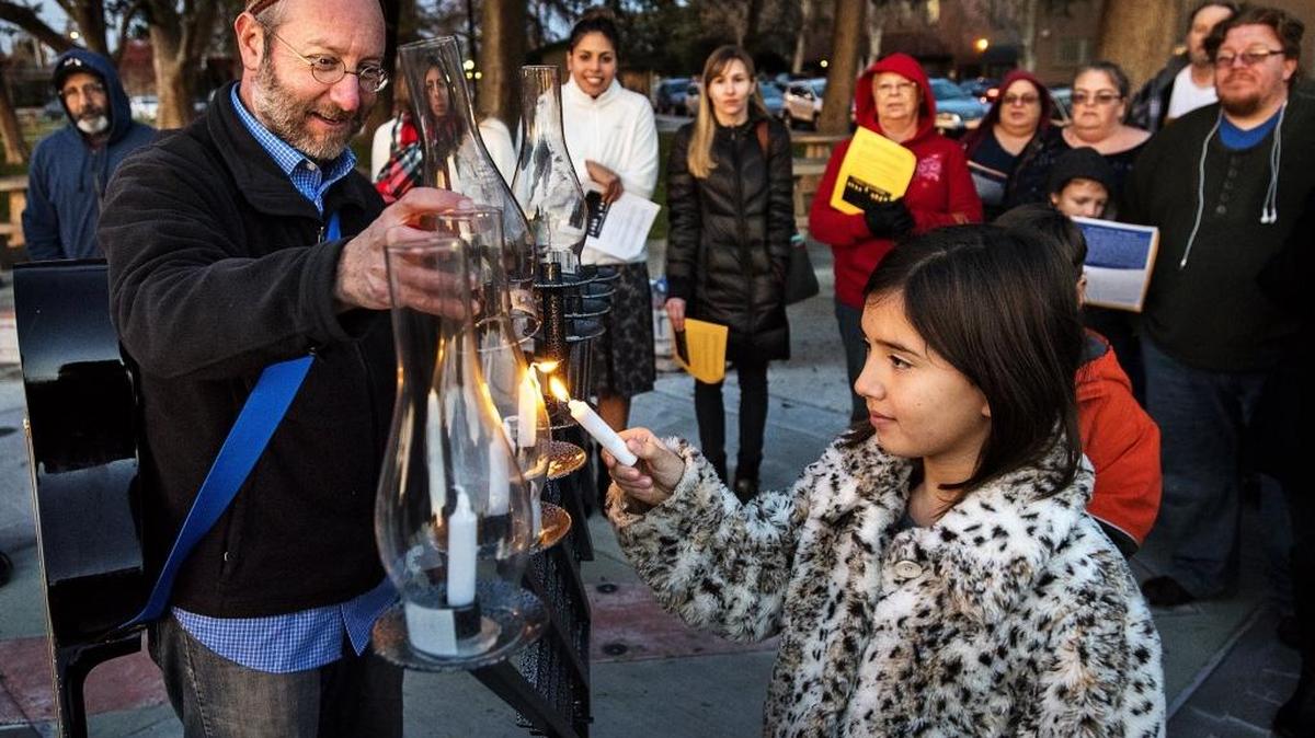 Paige Goodman, 10, of Manteca, helps Rabbi Shalom Bochner of Modesto’s Congregation Beth Shalom light the menorah at Library Park in Manteca on Monday, Dec. 26, 2016.