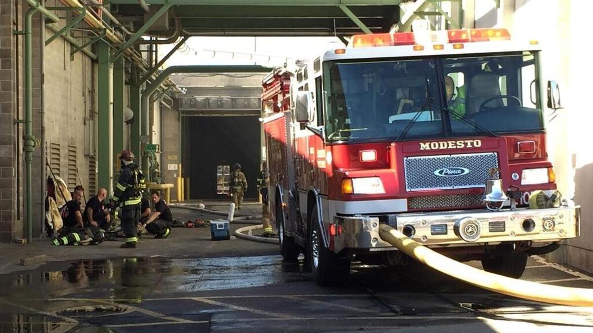 
Firefighters take a break to cool down while working to find and extinguish a blaze burning inside a wall at the former Olam Spices facility on East Whitmore Avenue in Modesto on Monday.
