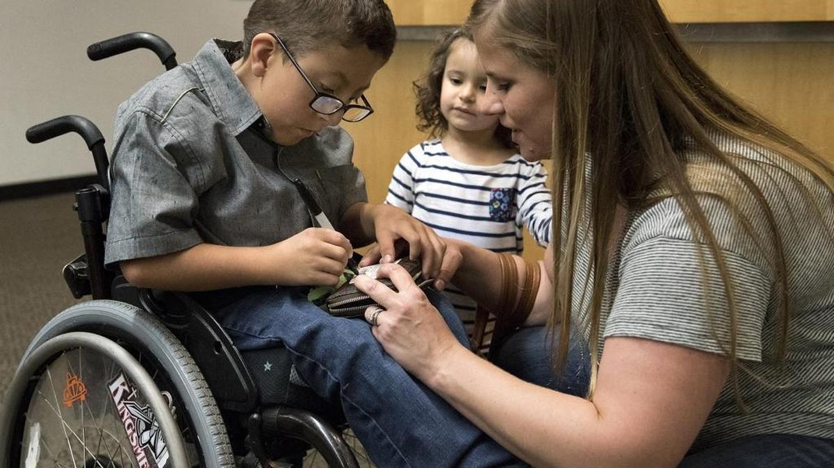 Tommy Loredo, 8, signs for his first library card with his mother, Rachel, and sister, Annaise, 2, at the Salida library on Thursday, March 3, 2016. Tommy was born with arthrogryposis, or contractures that limit his joint movement, and uses a wheelchair. Rachel Loredo is spearheading an effort to bring to Modesto what’s called an inclusive playground, on which disabled and non-disabled children can play side by side.