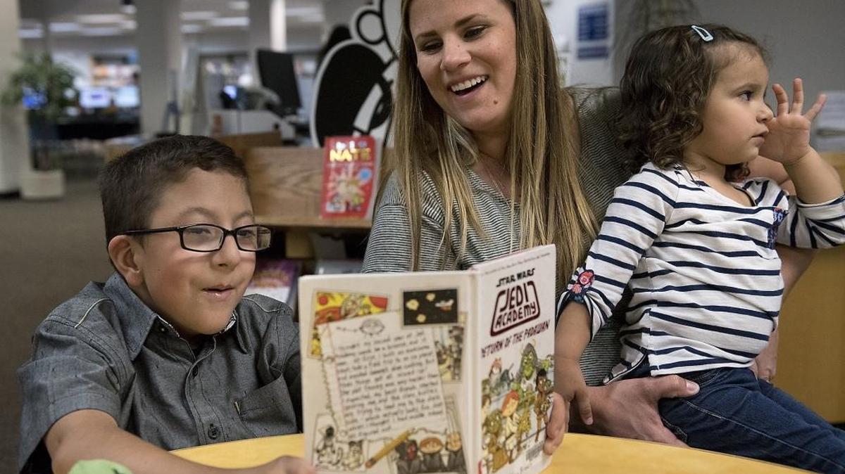 Tommy Loredo, 8, reads to his mother, Rachel Loredo, and sister Annalise, 2, at the Salida Library on March. 3, 2016. Tommy was born with arthrogryposis, or contractures that limit his joint movement and uses a wheelchair. Rachel Loredo is spearheading an effort to bring to Modesto what's called an inclusive playground on which disabled and nondisabled children can play side by side.