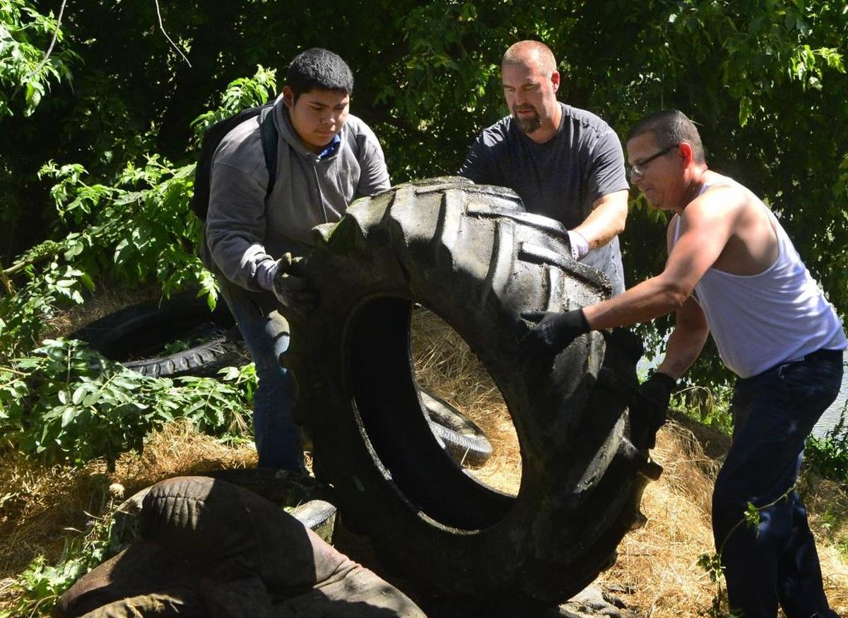 Volunteers Jorge Medina, left, Chris Guptill, center, and Marvin Eugene Salazar, right, move tires found in the Tuolumne River in Modesto during the Operation 9-2-99 cleanup effort in 2016.