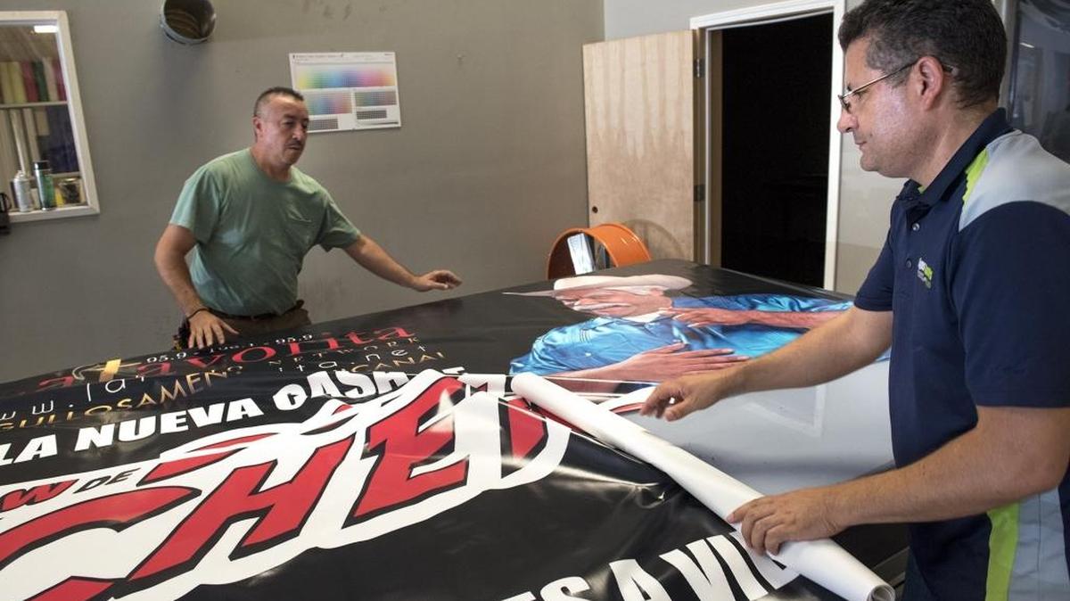 
Signs and Banners Express employee Carlos Leon, left, and owner Ramiro Laiton roll out a banner in Modesto on Wednesday. Officials will hold a news conference Thursday at the business to publicize the Grow Modesto Fund, a program providing loans to small business that can’t get conventional bank loans.
