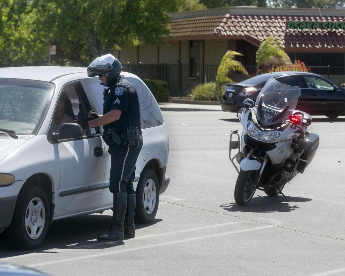 Modesto police Sgt. Aaron Tait talks with Elvira Rosas after pulling her over on suspicion of using her cellphone while driving in Modesto, Calif., on Saturday, April 30, 2016, as Modesto Police Motor Patrol officers were out looking for distracted drivers on their cellphones.