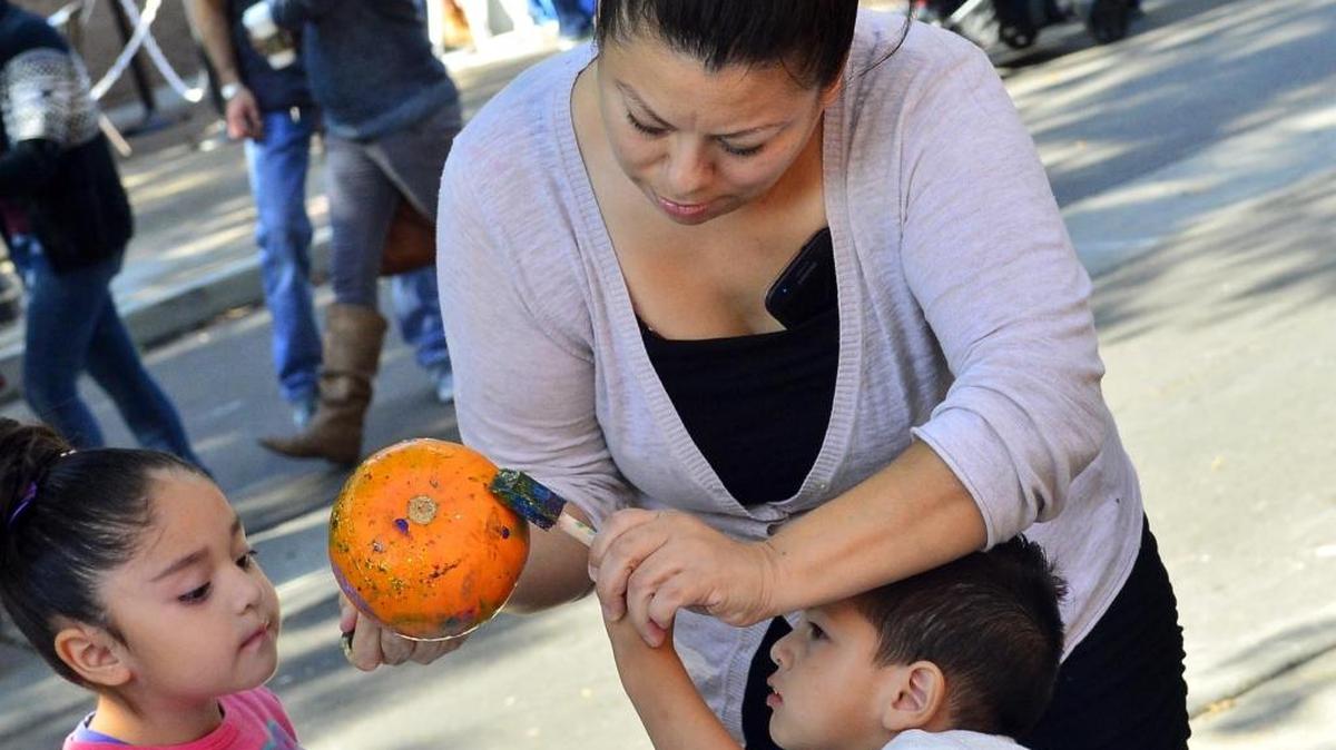 Raquel Hernandez helps Jaden Hernandez, age 2, paint a pumpkin during the Harvest Festival at Tenth Street Plaza in Modesto on Saturday, Oct. 15.