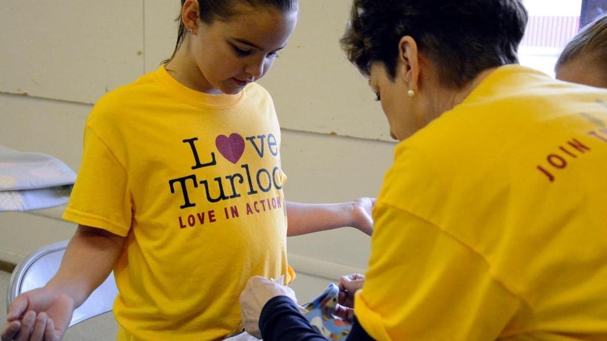 Some 700 volunteers took part in the communitywide service day known as Love Turlock on Saturday, May 7, 2016. Here, Becky Schlecht shows her granddaughter Savannah van Gaalen how to knot a blanket that will be donated to homeless mothers and children.