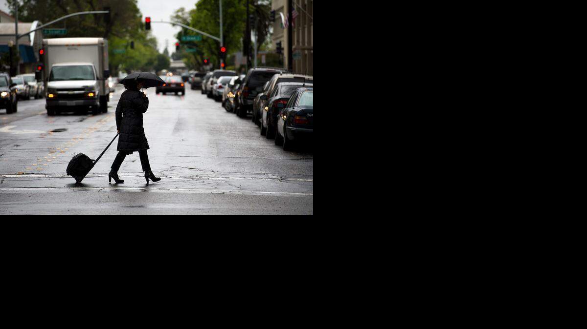A woman crosses 12th Street in Modesto on a wet Tuesday. A bit less than half an inch of rain had fallen by 5 p.m., according to MID’s downtown gauge.