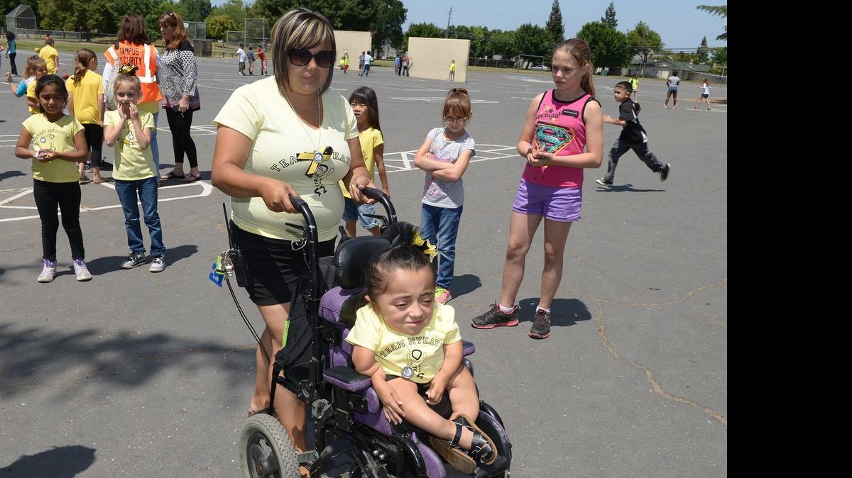 
Mykayla Herrera, 9, is pictured with her mother Wednesday afternoon at Sonoma Elementary School in Modesto. Mykayla has a rare condition called osteogenesis imperfecta, also known as brittle bone disease. Kids at Sonoma School wore yellow T-shirts with the OI emblem for Wishbone Day.
