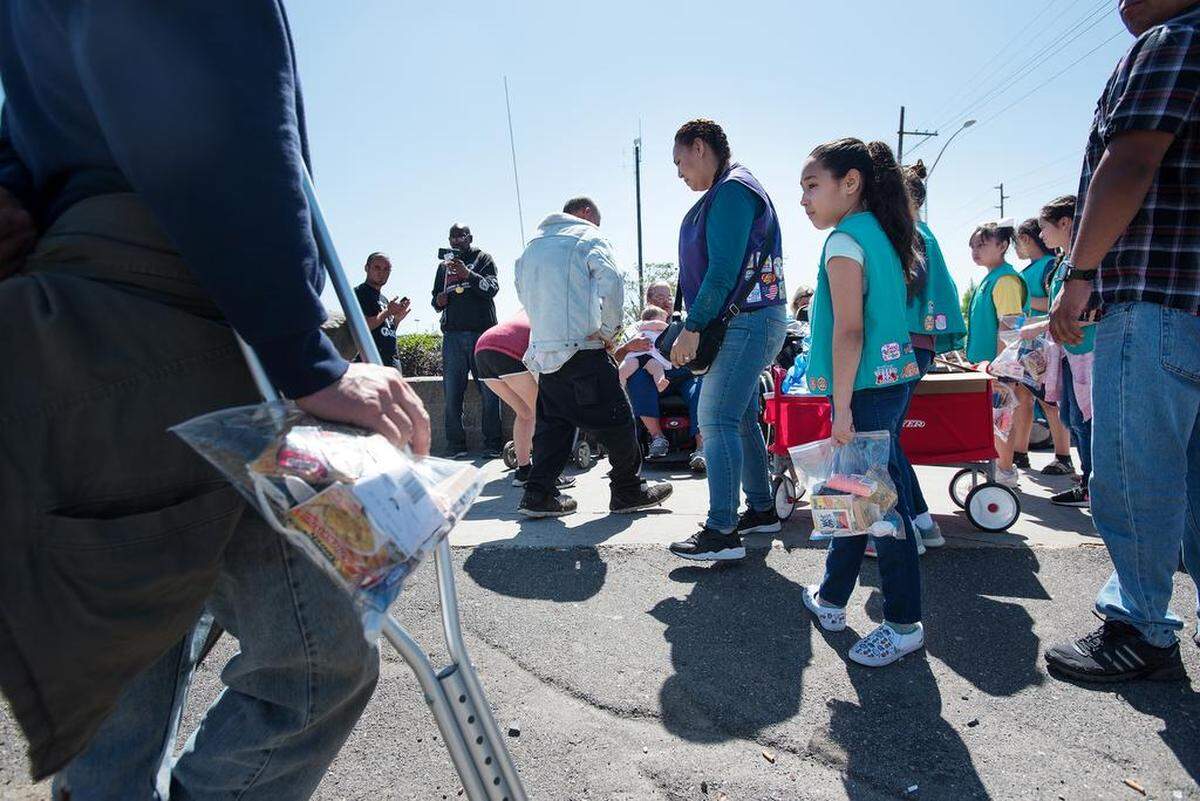 Girl Scout Kristianna Holquin, 9, middle, troop leader Emily Maeyama, middle left, and her troop members from Ceres, hand out care packages to homeless people in downtown Modesto, Calif., on Saturday, April 14, 2018. The girls from troop 3269 spent two months gathering donations to assemble the package of toiletries and snacks for their yearly community service project.