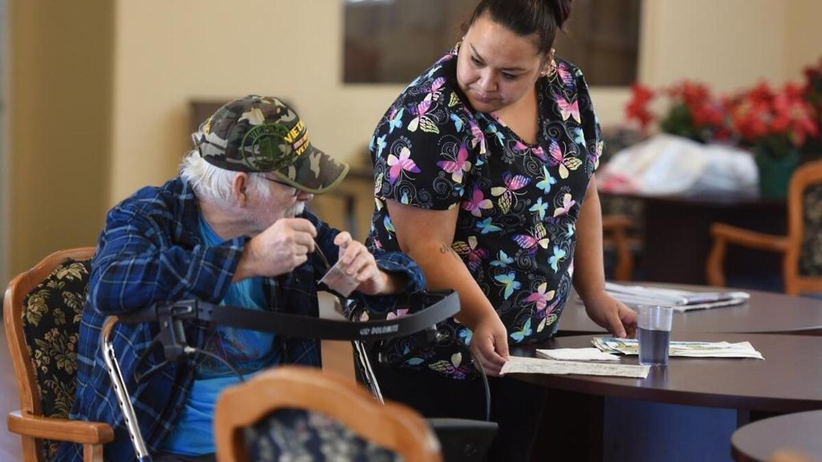 Caregiver Ernestine Espino talks to client Danny Lacky on Friday afternoon in the adult day care program at ResCare in Modesto.