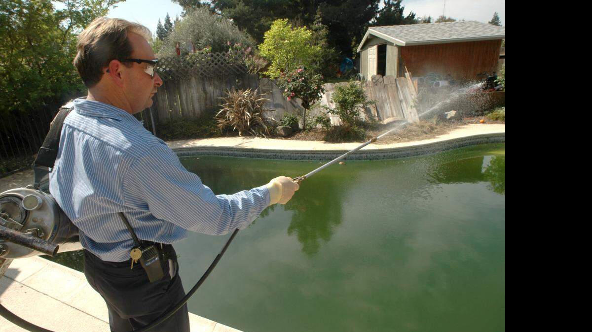 Mel Pinney of the Turlock Mosquito Abatement District treats a stagnant swimming pool at a vacant home in Denair in 2007.