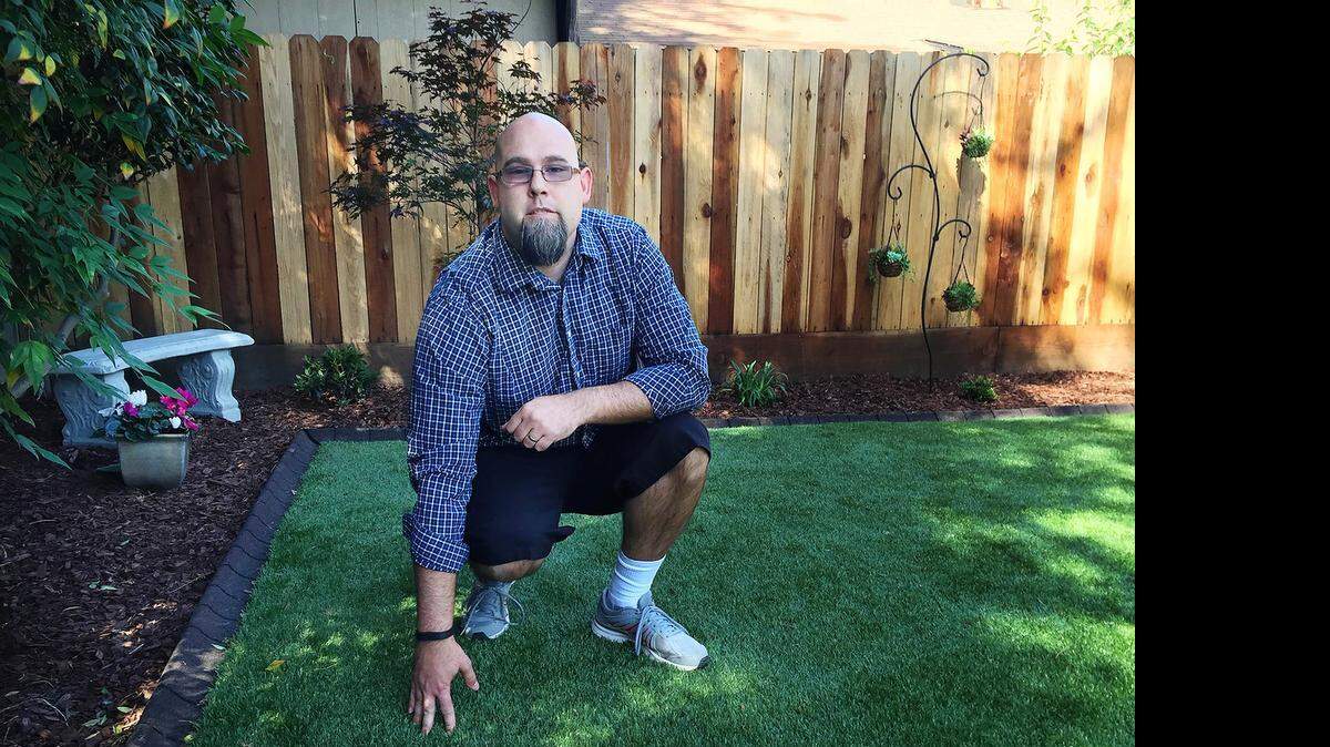 
Ryan Cheney of Modesto shows off the artificial turf he installed in his backyard through the HERO loan program, which pays for water- and energy-saving projects.
