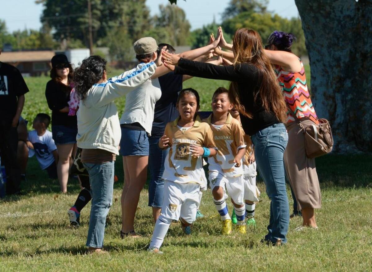 Parents make an impromptu bridge for their soccer players to pass through after their game at Fairview Park where south Modesto community group Manos Unidas, or United Hands, has been working to improve the park and raise money to make more improvements.
