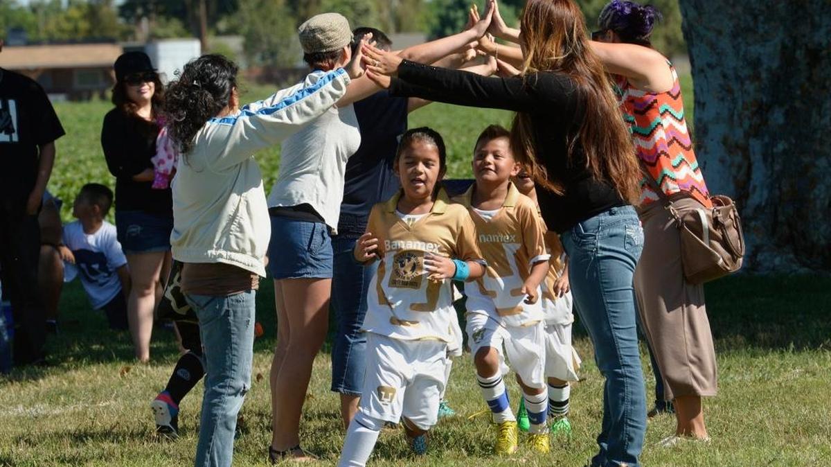 Parents make an impromptu bridge for their soccer players to pass through after their game at Fairview Park where south Modesto community group Manos Unidas, or United Hands, has been working to improve the park and raise money to make more improvements.