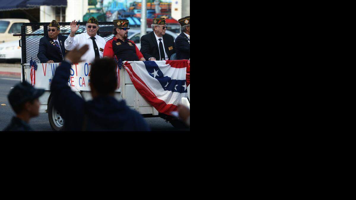 
Denise Haflich, center, with son Michael at her side, waves at veterans as the parade passes during Veterans Day in Modesto on Tuesday, Nov. 11, 2014.
