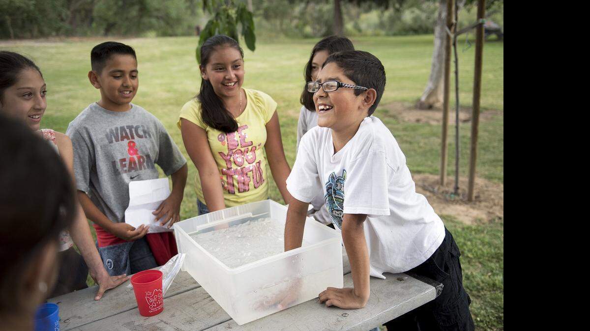 
Ian Navarro, 11, puts his hand in ice water to learn what the water would feel like in the local canals Tuesday during the Waterford after-school program’s Tuolumne River education fair, called Water Works, at River Park. 
