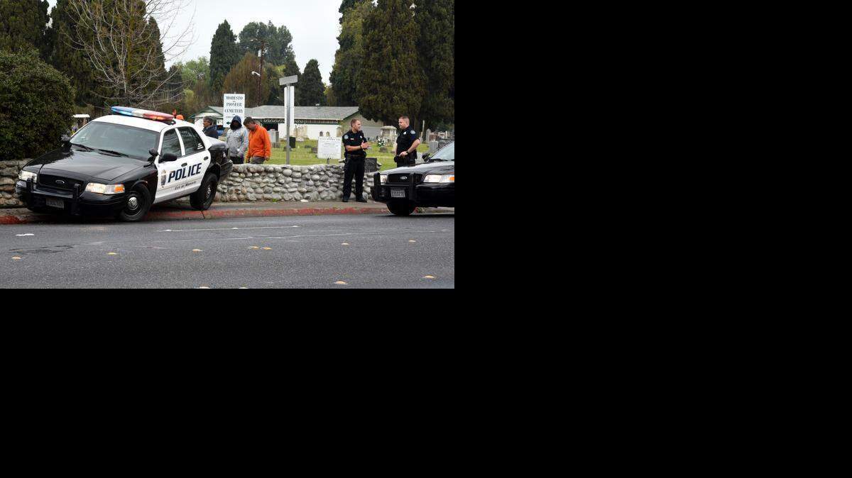 
Modesto police officers wait Wednesday for a tow truck to arrive to remove a patrol car from the St. Stanislaus Cemetery wall  on Scenic Drive near Bodem Street. Streets were wet from about a quarter inch of rain.
