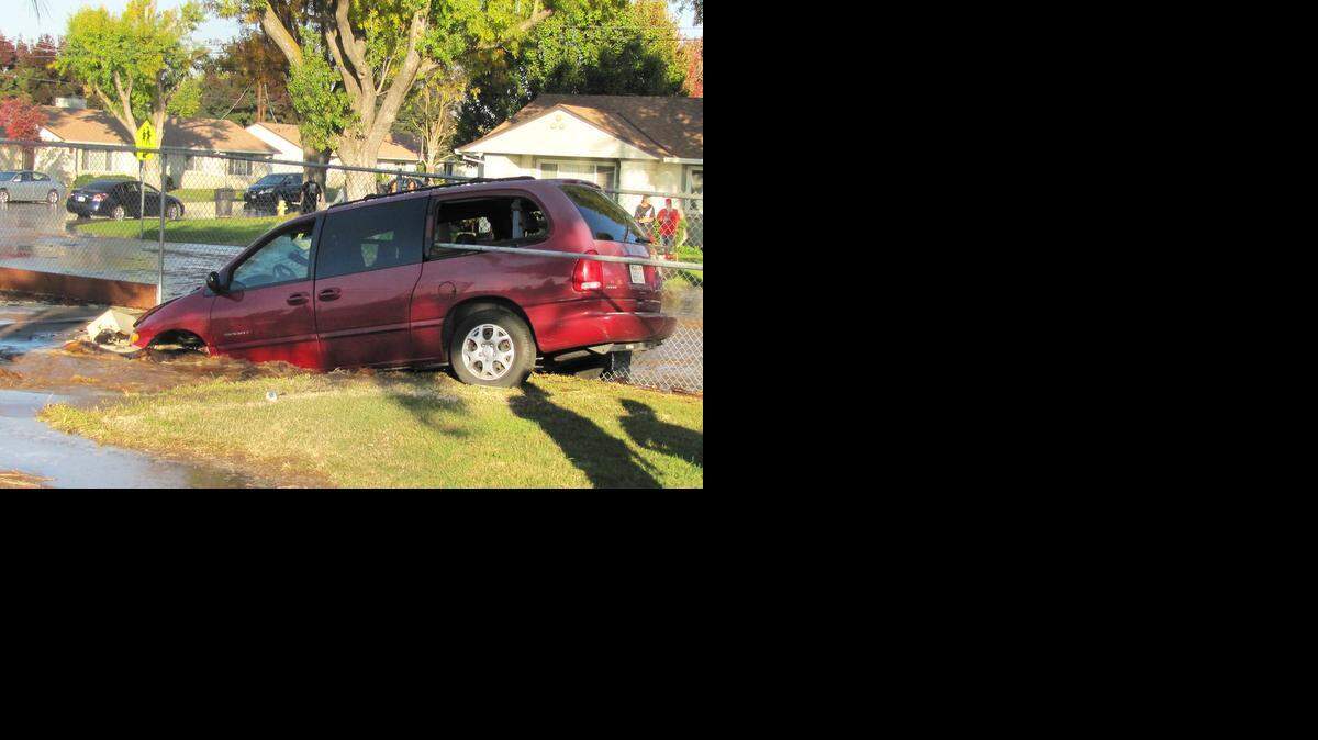 
A minivan sits partially submerged in a sinkhole caused by flooding from a water main that ruptured when the vehicle struck it near Robertson Road Elementary School on Friday.
