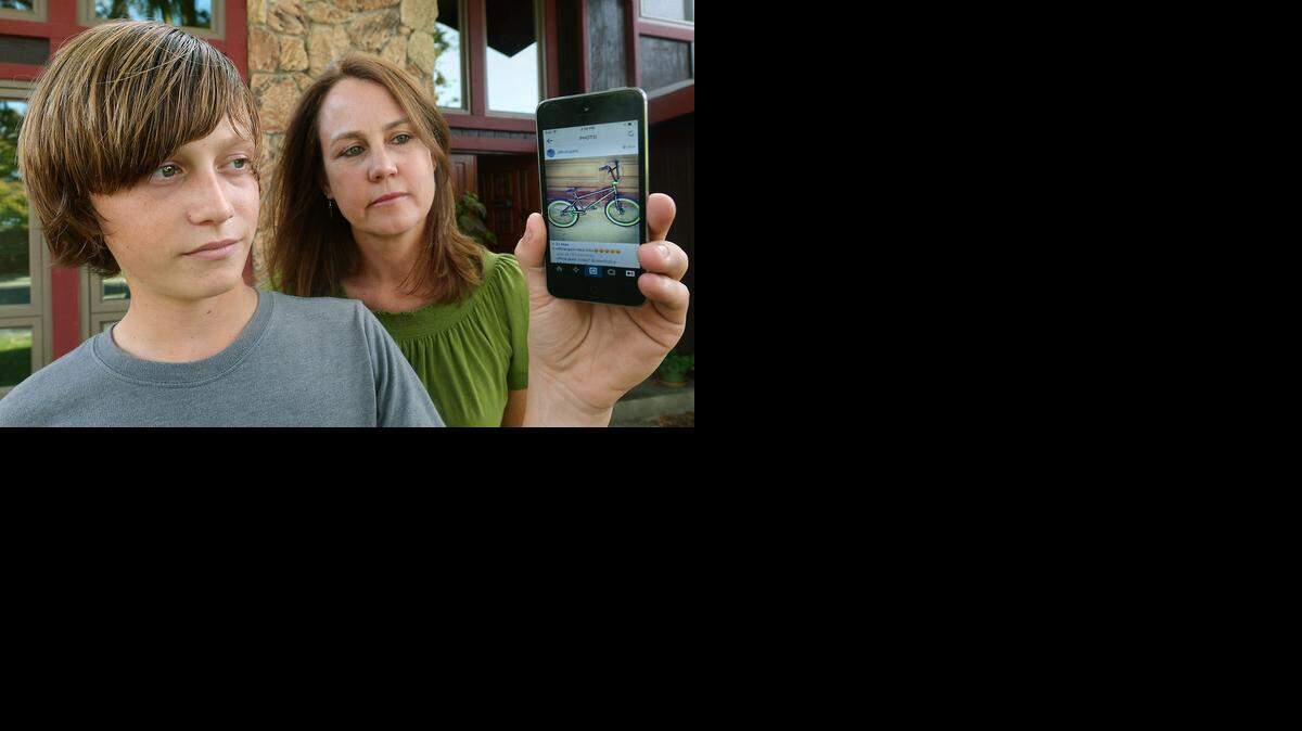
Collin Gunn, with his mother, Brenda, shows a photo of him jumping his bike at a track. Collin, 12, had his BMX bike stolen when he and friends stopped to get ice cream after school at Burger King. Brenda Gunn tracked down surveillance photos from a nearby business in efforts to find the thief.
