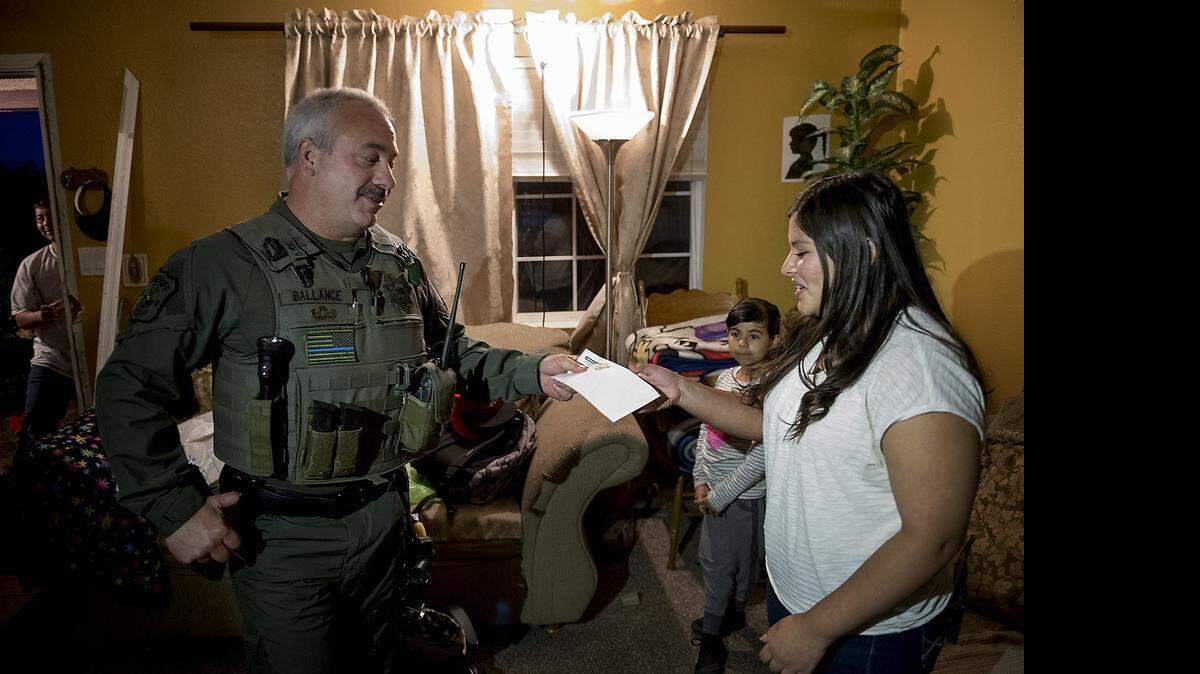
Stanislaus County Sheriff deputy Barry Balance gives Leonela Osuna, 14, a gift of $1500, money raised through donations in the department, to replace money she had saved for her quinceañera which was stolen yesterday.
