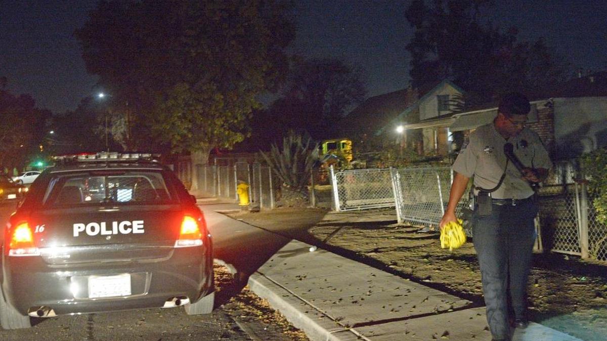 An Explorer with the Modesto Police Department walks along the sidewalk after a reported shooting in the area of Thrasher Avenue on Friday, Nov. 20, 2015.