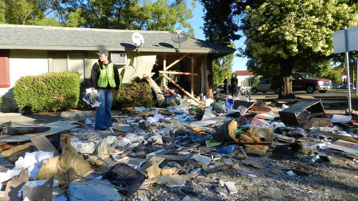 A two-door black sports car crashed into and out of a triplex unit on the 300 block of College Avenue in Modesto on Wednesday morning, Nov. 4, 2015. The vehicle went through the living room and bedroom about 5:45 a.m., but the resident already was up and in the kitchen. He was unhurt. Here, the resident's caregiver, Gloria Serrano, looks over belongings the crash carried into a vacant lot next to the triplex.
