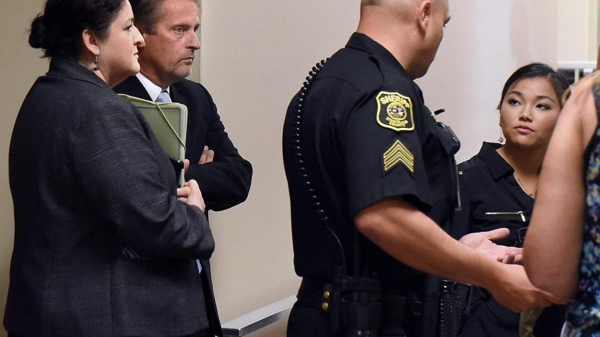 Tracy Bull, second from left, listens to a sheriff’s deputy talk to a reporter about access to the courtroom. Bull made his first court appearance Friday morning, July 15, 2016, in Stanislaus Superior Court in Modesto, Calif. The longtime head coach of the Ceres Dolphins Swim Team is accused of misconduct with two teenage girls, at least one of whom was on his swim team.