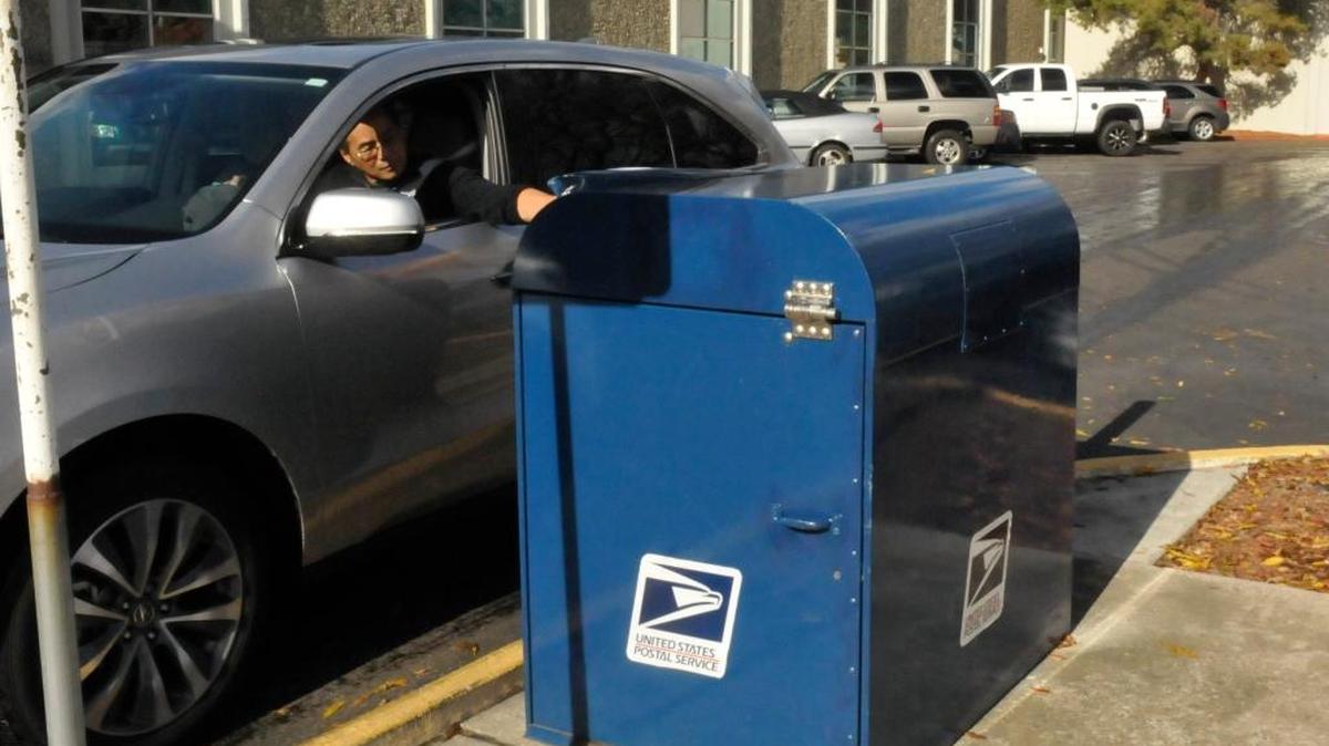 A reinforced mail collection box outside the Kearney Avenue post office in Modesto still was cracked by thieves. Here, a customer uses the box Friday, shortly before it was removed.