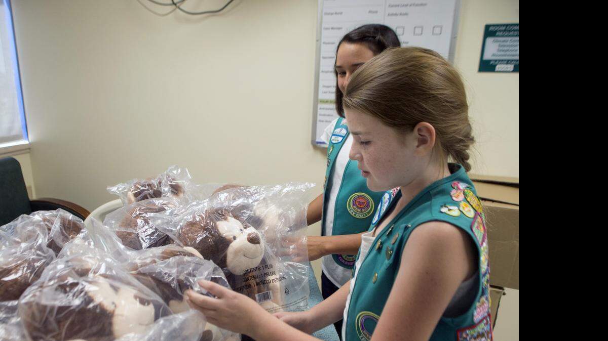 
Girl Scout Troop 4077 Cadette Kora Elkins arranges a donation of stuffed monkeys with Cadette Julia Shannon behind her at the pediatrics unit of Memorial Medical Center on Sunday. The toys were part of the girls’ Bronze Award project.
