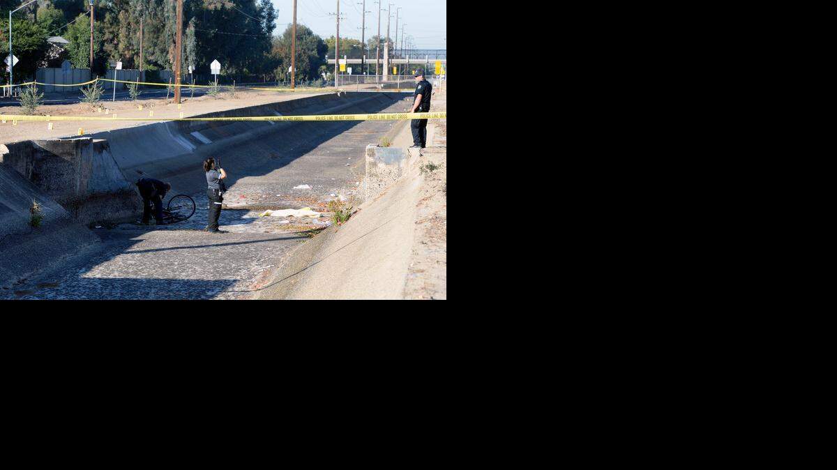 
Modesto police officers work the scene where a cyclist was found dead in a canal on West Briggsmore Avenue at Aloha Way on Wednesday.
