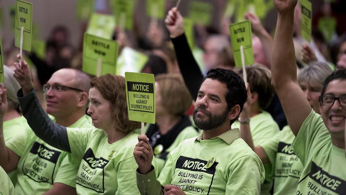From left, Jennifer James, Yaser Herrera and David Madrigal join others in holding signs as school board members take their seats before Tuesday’s Modesto City Schools meeting at Gregori High on Tuesday, Feb. 9, 2016.