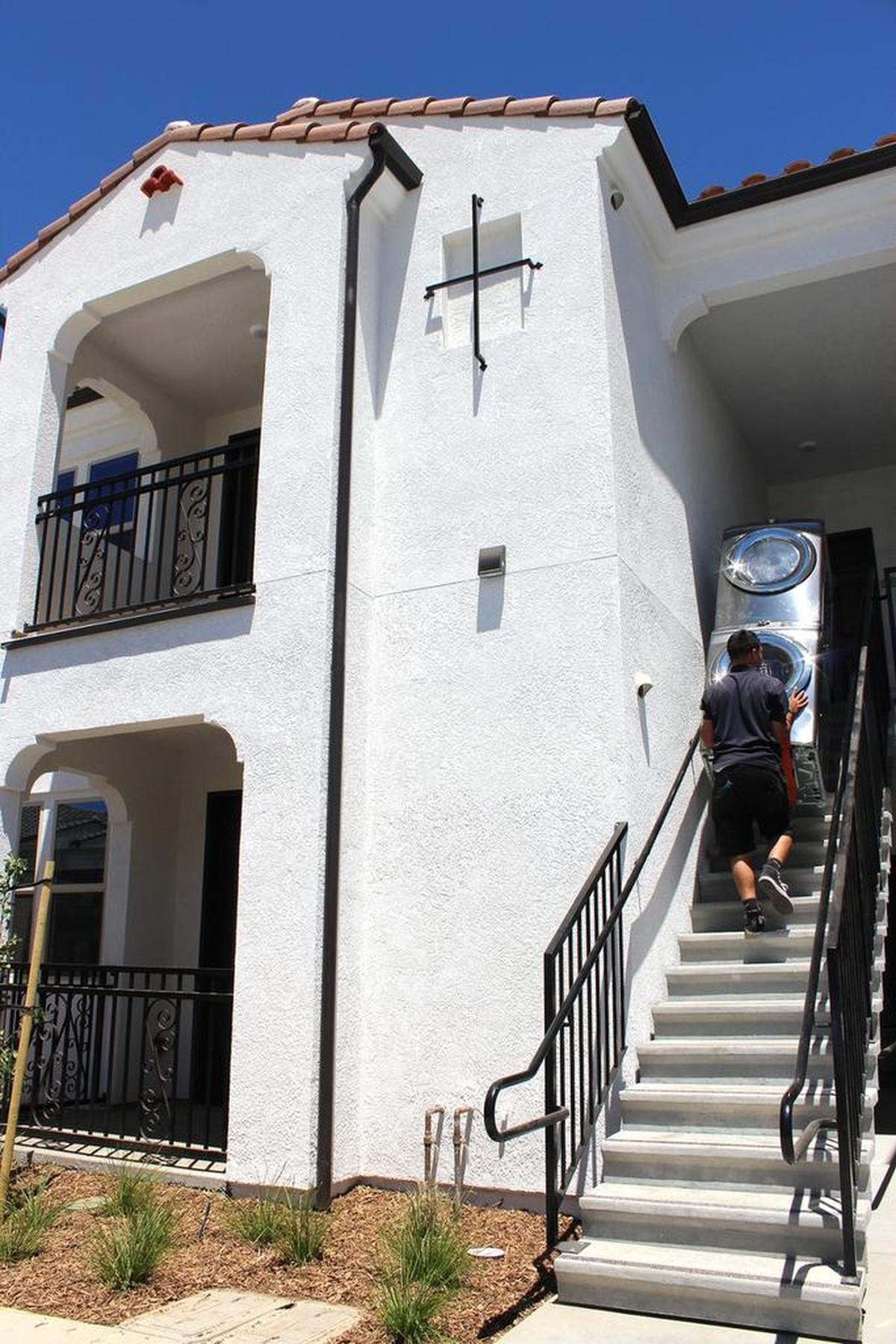 Workers deliver a stacked washer-dryer set July 20, 2016, to the upstairs unit of two apartments in Patterson, Calif.