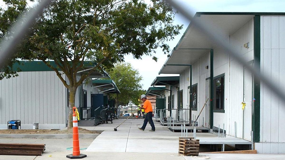 
Workmen finish the walkways Thursday surrounding 14 new portables in the large rear parking lot at Johansen High School before math and science teachers can get in and set up their new digs. Wires were still being strung to new power poles erected by what is being called the E wing. An electrical fire in June ruined the interior of the B building at the Modesto campus.
