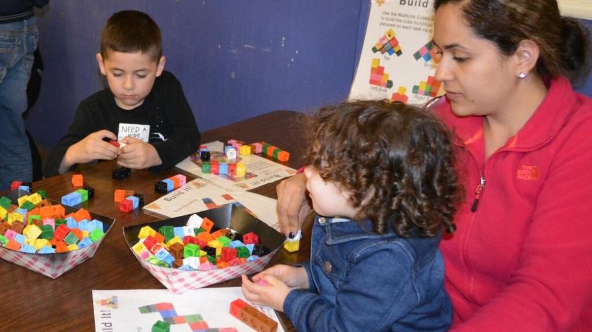 Jose Mendoza, 5, works on a math puzzle while mom Claudia Mendoza helps sister Violetta, 2, snap counting blocks together at an Aspire Summit Charter Academy math night in Modesto on Feb. 18, 2016.