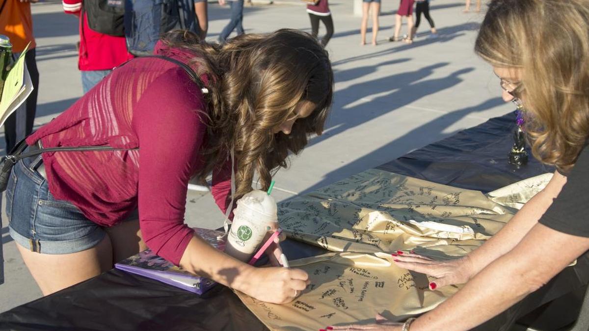 
Senior Kelly Hudson signs a graduation gown during the first day of school at Enochs High School in Modesto on Monday.
