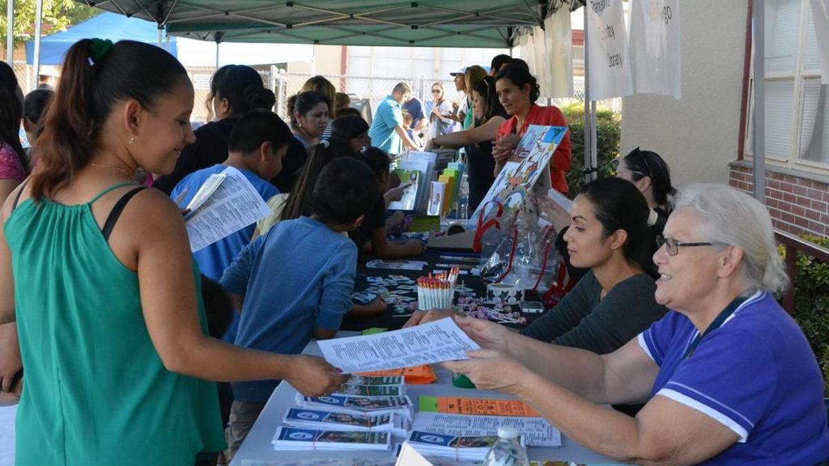 
Families pick up information on services available, and free pencils and stickers, walking down the line to free hot dogs at a family evening at Tuolumne Elementary School in south Modesto on Sept. 24, 2015.
