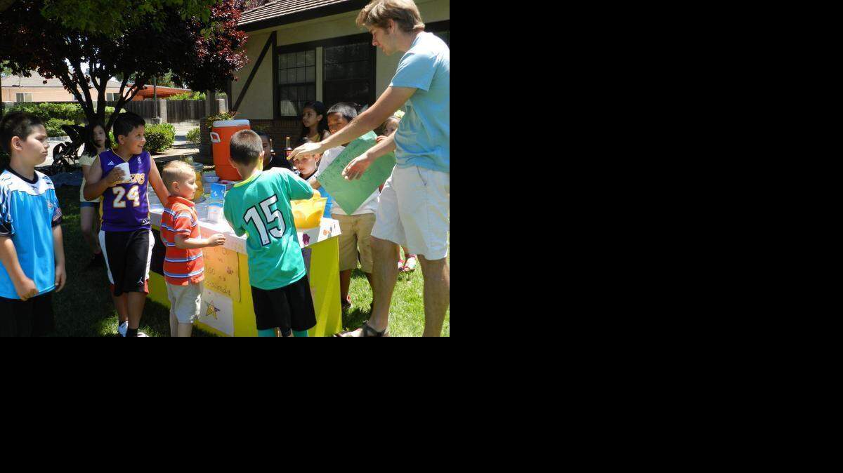 
Josh Branco, program manager at Connections Family Center, guides the children running the organization’s Lemonade Day stand in 2013.
