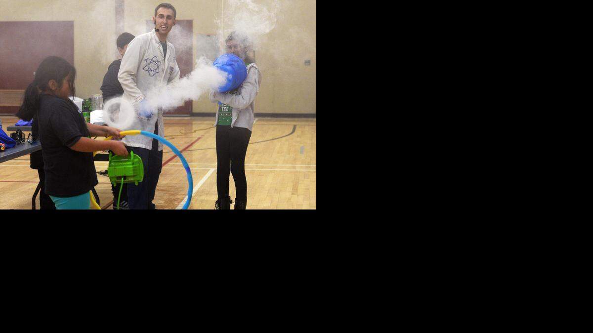 
Student volunteer Marissa Juarez-Martinez, 8, holds a hoop as Kaory Garcia, 11, shoots a smoke ring from the airzooka vortex cannon. Jeffrey Vinokur, known as “The Dancing Scientist,” teaches science to an audience of mostly Franklin Elementary School students and their families at the Mark Twain Junior High School gymnasium on Friday.
