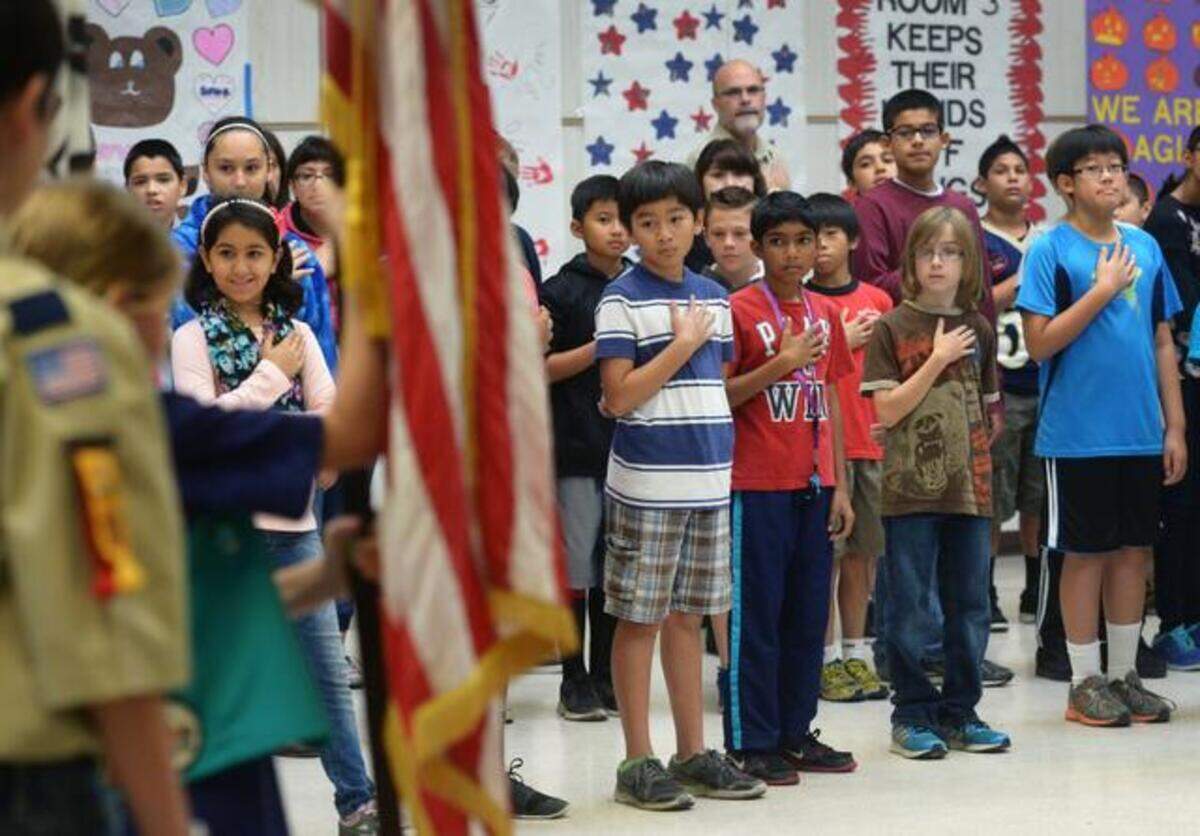 Students with hands over hearts stand as the Scout color guard enters. Veterans were recognized and honored in school assemblies and later class visits at the Veterans Day ceremony held at Agnes Baptist Elementary School, Nov. 10, 2014.