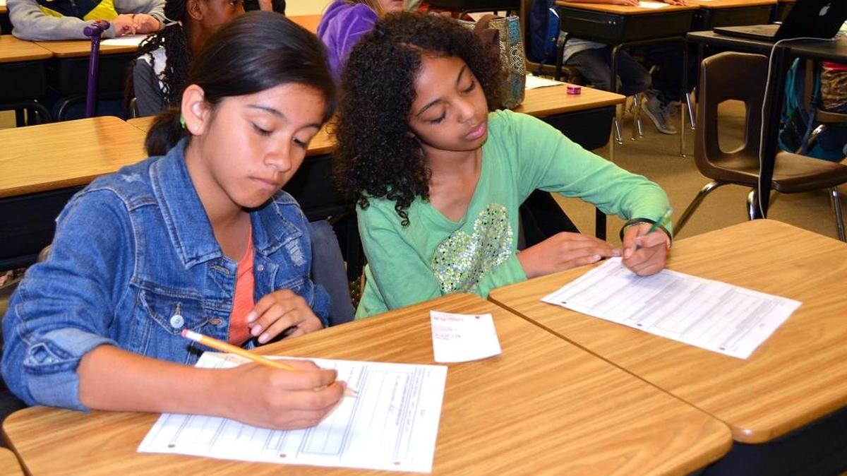 Juliette Roundtree, on right, and Gianni Juarez work on career day assignments as the speaker talks at Somerset Middle School in Modesto, Calif., on March 21, 2016.
