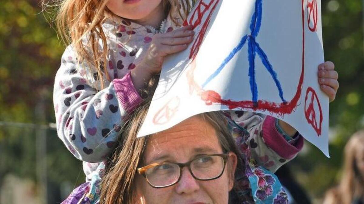 Ruthie Roseman, 4, holds a peace sign Wednesday while sitting on the shoulders of her mother, Rachel, at a solidarity rally at California State University, Stanislaus, in Turlock to show support for immigrants.
