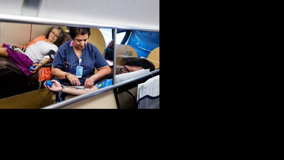 
Registered nurse Maria Vega, middle, tends to Will Hinrichs as he and Lupe Valdez, left, have their blood drawn on a BloodSource mobile donation bus at Regal Cinemas on McHenry Avenue in Modesto on Sunday. Each donor gave a pint of blood, and afterward they received a free movie ticket.
