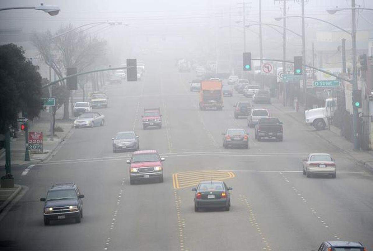 Cars drive in the fog on Ninth Street near the Kansas-Needham overpass Thursday, with and without headlights.