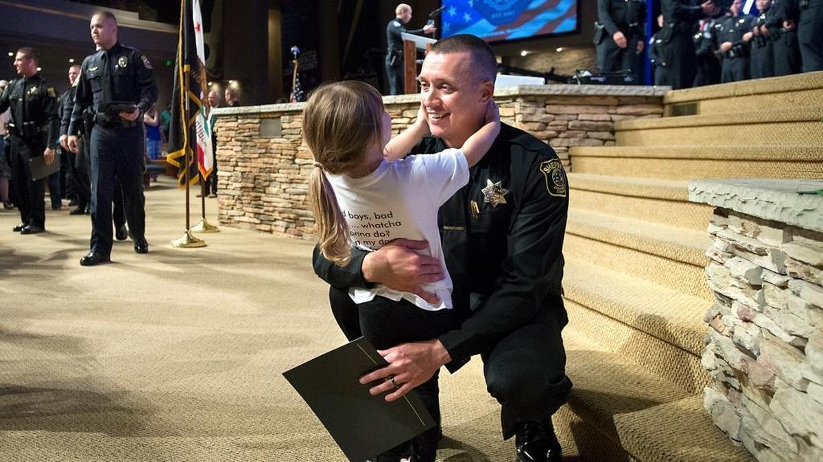 
Newly sworn Stanislaus County Sheriff's Deputy Joshua Lancaster receives a hug from his daughter Kenzie, 3, after being sworn in during the law enforcement academy graduation at The House church in Modesto, Calif., on Friday, September, 11, 2015. 
