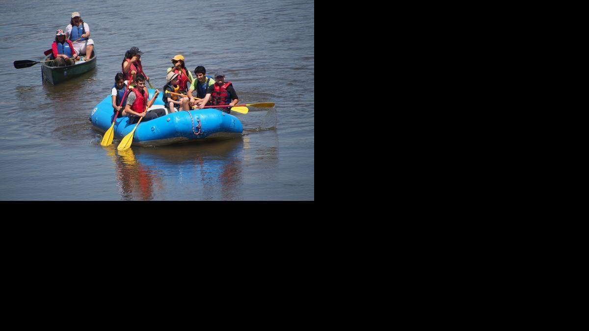 
A canoe and raft are paddled down the Tuolumne River. 
