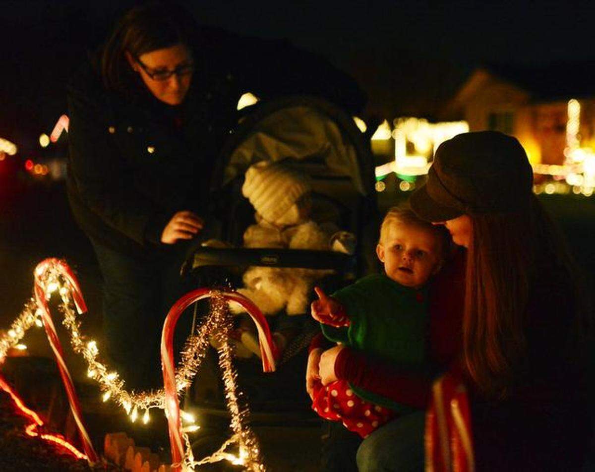 At right, Isla Mize, 1, looks at festive displays of lights along Christmas Tree Lane in Ceres with her mom Christina, and 1-year-old cousin Evelyn Mize and her mom Whitney Mize on Thursday. 
