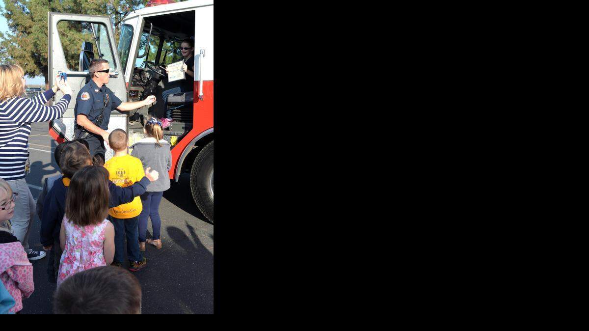 
Stanislaus Consolidated firefighter Gary McAndrews gives second-grader Elenore Thompson a seat behind the wheel while kindergarten teacher Kelli Mori records the moment at Big Valley Grace Christian School in Modesto on Friday.
