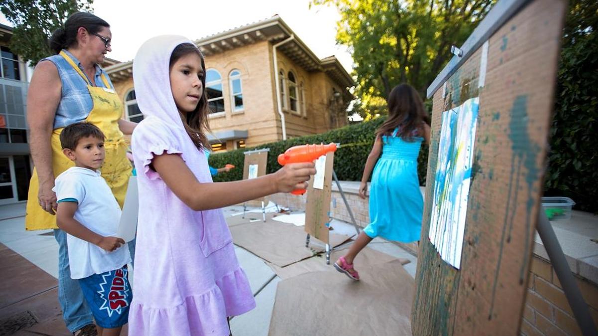Cassondra Montanez, 9, makes a painting using colored water in a squirt gun during the Say Yes to the Mess event, part of the Family Friday series, at the Carnegie Arts Center in Turlock, Calif., on Friday, July 22, 2016. The Carnegie Arts Center celebrated colorful characters with a family night of spraying, splattering and stomping with paint.