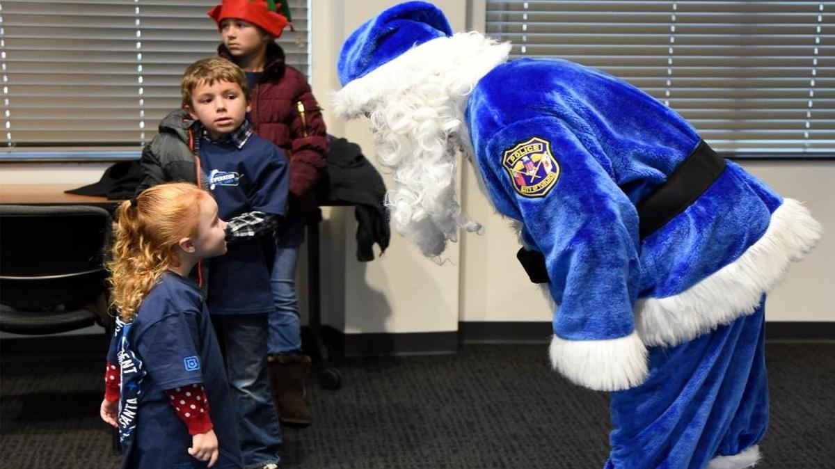 Landry Shaw, 3, checks out Blue Santa on Friday as her brother Mason, 7, looks on at the Turlock Public Safety Center. The kids and Santa were on hand for Operation Blue Santa, a program that brings Christmas to needy families.