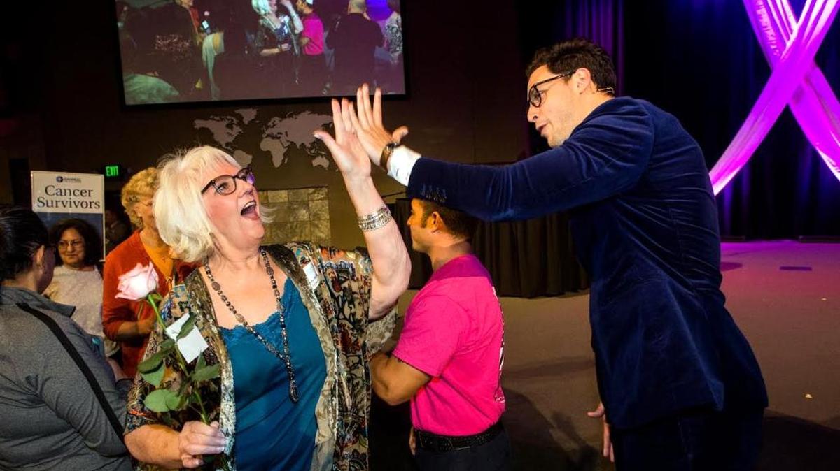 Sandy Bettencourt gives Dr. Mikhail Varshavski a high-five as she walks in the survivor procession Tuesday evening during the Emanuel Medical Center Women's Cancer Awareness Night Out at Monte Vista Chapel in Turlock.